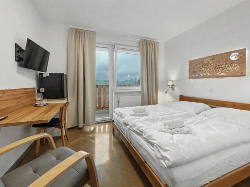 a bedroom with a bed and a desk with a computer at Wellness Apartmány Pastviny in Pastviny