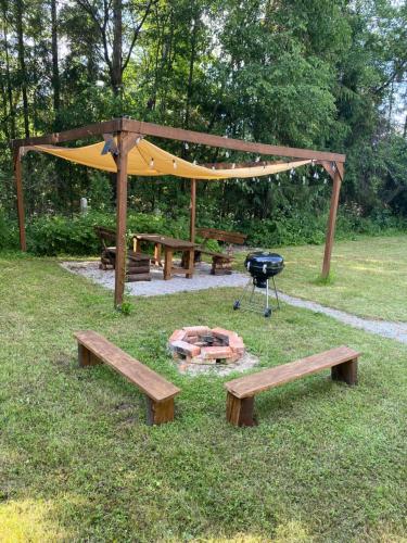 a picnic area with benches and a grill and a tent at koliBka - tiny house in Michalová