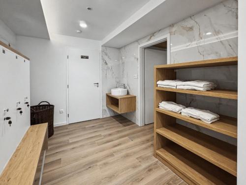a bathroom with white walls and wooden shelves at Wellness Apartmány Pastviny in Pastviny
