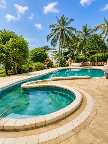 a swimming pool in a resort with palm trees at Tropical Court 2 BedroomDiani Beach villa in Kwale