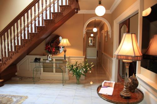 a hallway with a staircase with a table and a lamp at Ashville House B&B Tralee in Tralee