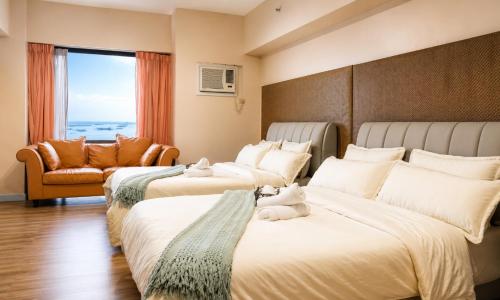 a hotel room with three beds and a chair at Tripleview luxurious eton baypark manila in Manila