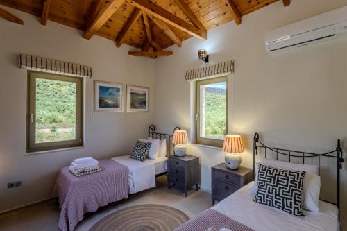 a bedroom with two beds and two windows at The Olive Grove Kardamyli in Kardamyli