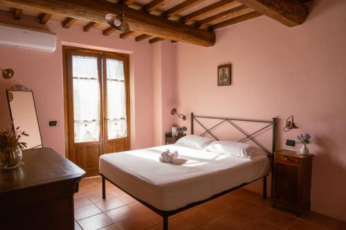 a bedroom with a bed in a room with pink walls at Poggio Mille in Castiglione del Lago