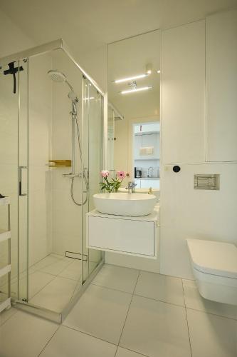 a white bathroom with a sink and a shower at WAVE Seaview in Międzyzdroje