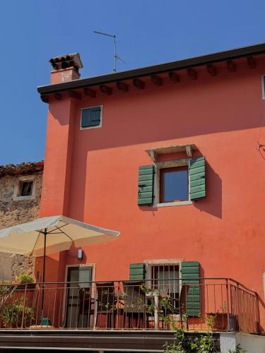 a orange building with a patio and an umbrella at Casa Olivia Bardolino - Garda Lake in Bardolino