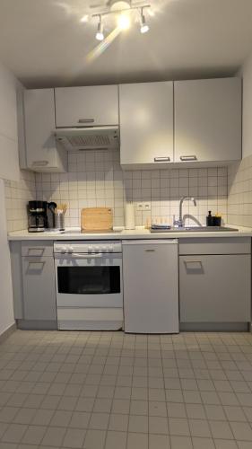 a kitchen with white appliances and white cabinets at Gemütliche 1-Zimmer-Wohnung im Hildesheimer Wald in Diekholzen