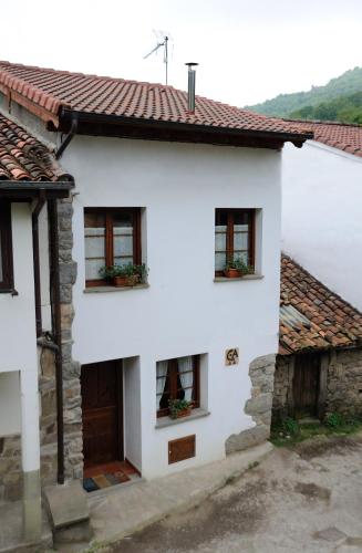 ein weißes Haus mit Fenstern und einer Tür in der Unterkunft Casa Guela in Pajares