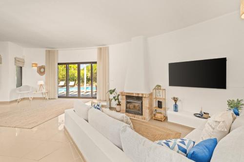 a white living room with a white couch and a tv at Vilamoura 4-Bedroom Private Pool Villa in Vilamoura
