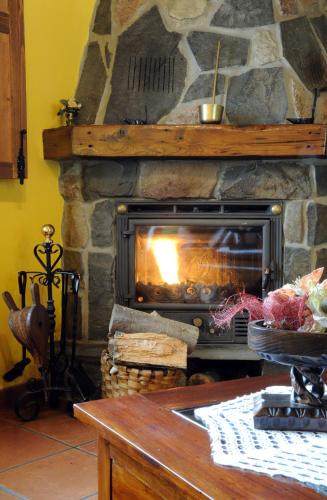 a stone fireplace with a fire in it at Casa Guela in Pajares