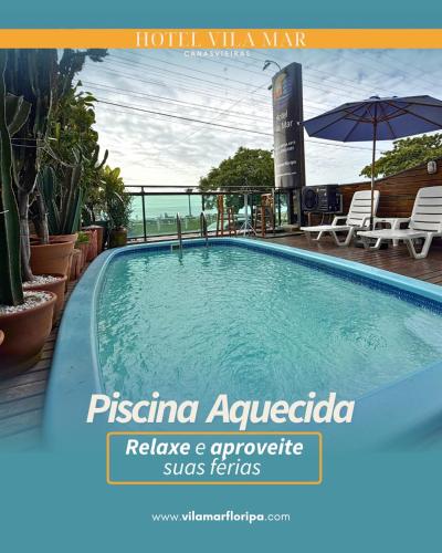 a swimming pool with chairs and an umbrella at Hotel Vila Mar in Florianópolis