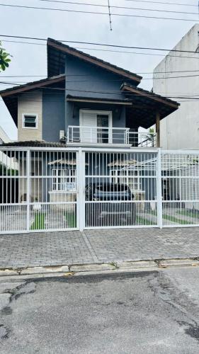 a white fence in front of a house at Pousada do Tio Cido in Guarujá