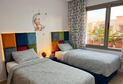 a bedroom with two beds and a window at Asilah Cozy Pieds dans l'eau in Asilah