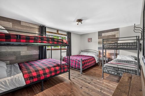 a room with three bunk beds in it at Le Sto Shack 25 Chemin Blanc by Les Chalets Alpins in Stoneham