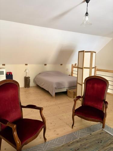 a bedroom with a bed and two chairs in it at Gite l'Entre Deux O' in Blesle
