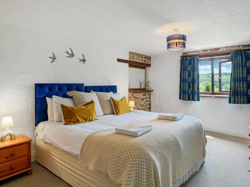 a bedroom with a large bed with yellow pillows at Jasper Cottage Hawkridge in Dulverton