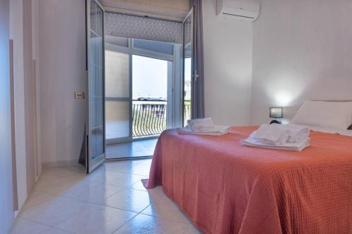 a bedroom with a bed with a red spread and a balcony at Casa Vacanza Colletta - appartamenti e lido in Casteldaccia