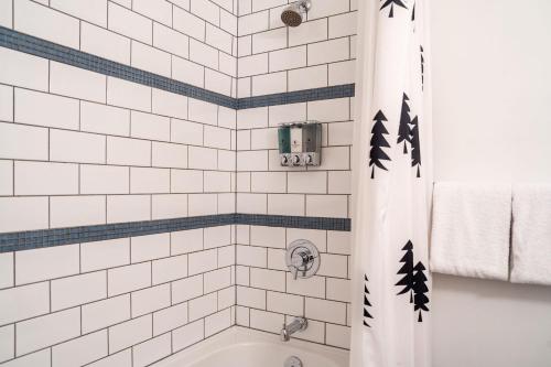 a white tiled bathroom with a tub and a shower curtain at Selkirk Snug by Revelstoke Vacations in Revelstoke