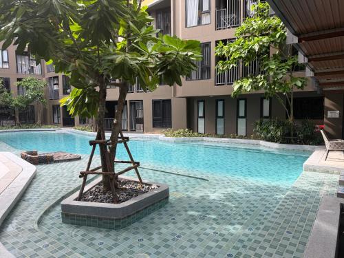a tree next to a swimming pool in a building at The Base Central Phuket-a modern comfort condo-sso in Ban Rangeng