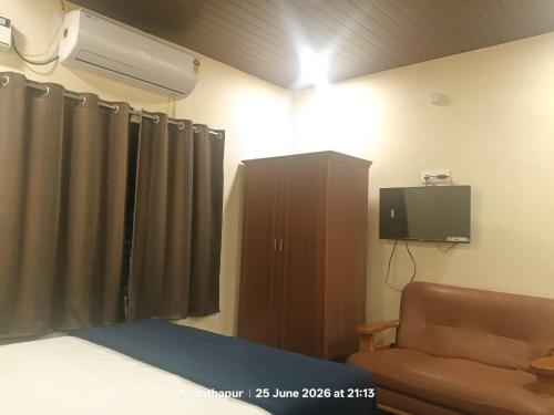 a bedroom with a bed and a tv and a couch at Vybhav Residency AC in Anantapur