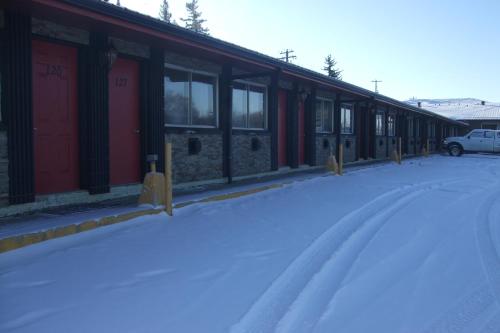 a snow covered building with red doors and windows at Trailside Inn in Lloydminster