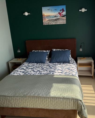 a bedroom with a bed with a green wall at Apartament Gardenia Sun in Międzywodzie