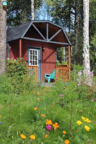 a red cabin in the middle of a field of flowers at DFA Cabin Rentals in Talkeetna