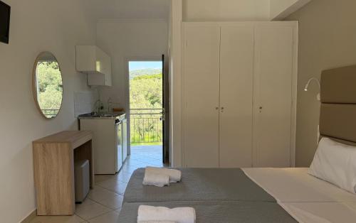 a white bedroom with a bed and a kitchen at Anemona Studios in Paleokastritsa