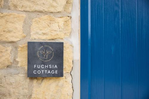 a sign on a stone wall next to a blue door at Fuchsia Cottage - Accessible Comfort in Wilton