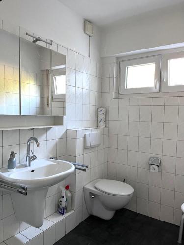 a white bathroom with a sink and a toilet at Sommer Gästehaus in Bremerhaven