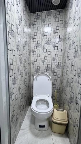 a bathroom with a toilet and a trash can at Gulzar Village Guesthouse in Dushanbe