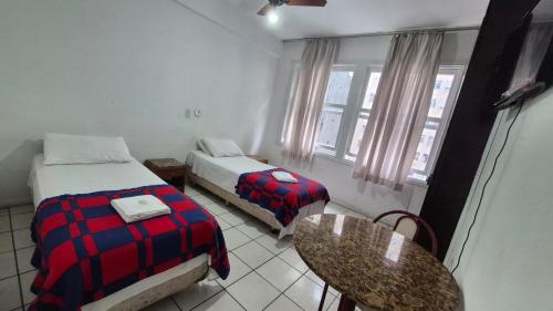 a hotel room with two beds and a table and a table sidx sidx at Hotel Manoá Poa - Ambiente acolhedor e humanizado, seu refúgio estratégico no centro de Poa, próx a UFRGS, rodoviária e a Santa Casa in Porto Alegre