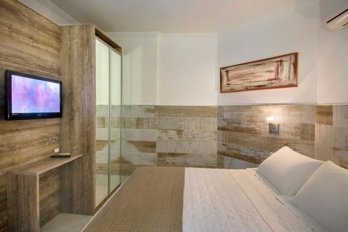 a bedroom with a bed and a tv on a wall at Pousada Bora Bora in Bombinhas