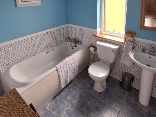 a bathroom with a tub and a toilet and a sink at 19 River Glen in Curracloe