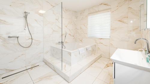 a bathroom with a shower and a tub and a sink at Strandhotel Orchidee in Sankt Kanzian