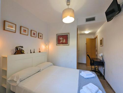 a bedroom with a white bed and a desk at Relax en Lloret con Gym y Piscina by Host&Joy in Lloret de Mar