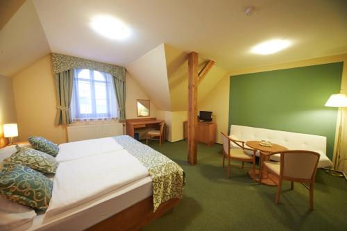 a hotel room with a bed and a table at Hotel Bílý jednorožec in Třeboň