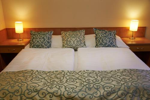 a bedroom with a bed with two lamps on it at Hotel Bílý jednorožec in Třeboň