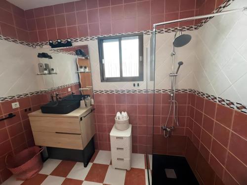 a pink tiled bathroom with a sink and a shower at Villa Gení in La Victoria