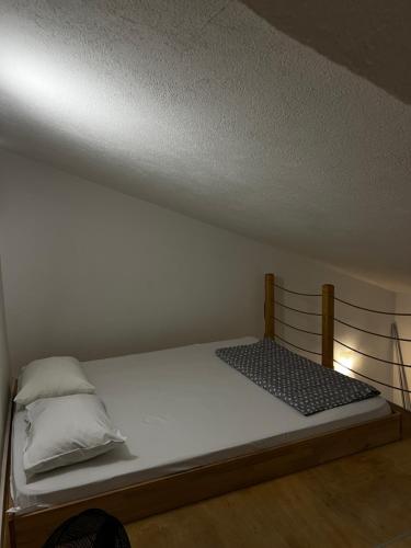 a bed in a room with a white wall at Tesla Apartman in Risan