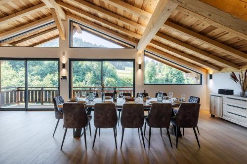 a dining room with a long table and chairs and large windows at Chalet des Granges 12 personnes Spa et cinéma in Morzine