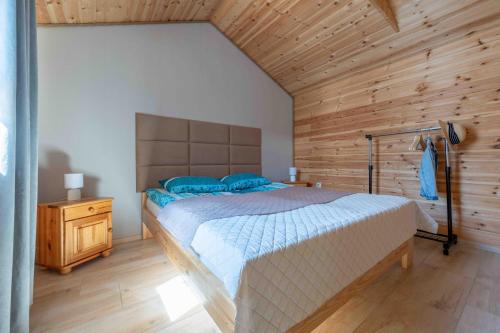 a bedroom with a large bed and a wooden wall at Domki letniskowe Ranczo in Darłowo