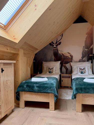 two beds in a room with a deer on the wall at Apartament Bioło Izba in Czerwienne