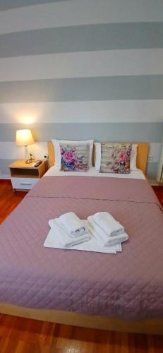 a bed with a purple bedspread with towels on it at Anna's Cozy Place in Sparta