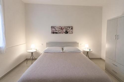 a white bedroom with a large bed with two side tables at Borgo San Michele Bed & Breakfast in Calvisano