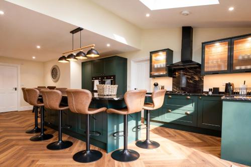 a kitchen with green cabinets and a bar with stools at The Nook in Claypits