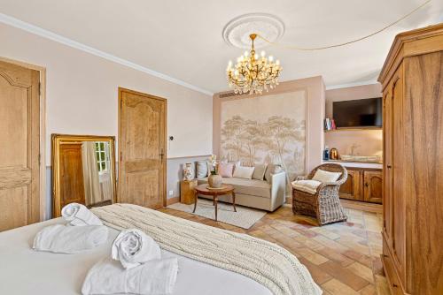 a bedroom with a bed and a couch and a chandelier at Maison Casasand Maison d'hôtes de charme in Grasse