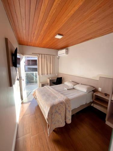 a bedroom with a large bed with a wooden ceiling at Hotel Ponto 1 in Vacaria