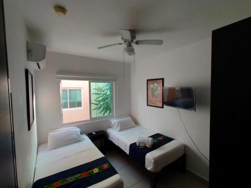 a small room with two beds and a window at CasaMEXH Lunamar - Despierta, toma café en la 5ta Av, explora Xcaret, experimenta Tulum o algún cenote cercano - Unas vacaciones extraordinarias para tu familia y tus amigos in Playa del Carmen