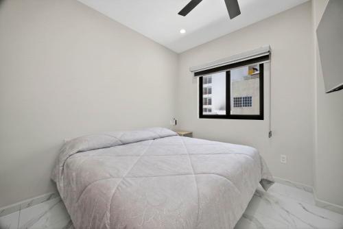 a white bedroom with a bed and a window at Unit Aguacates Romantic Zone in Puerto Vallarta